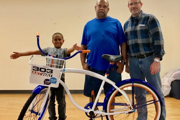 Eric Johnson (center) was the proud winner of a bike at 303 ArtWay's premier bike giveaway event. Will Kralovec, ULC's Director of Master Site Development, celebrated his win.