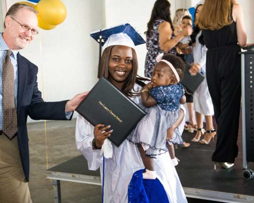A smiling graduate of New Legacy Charter School holding a very cute baby